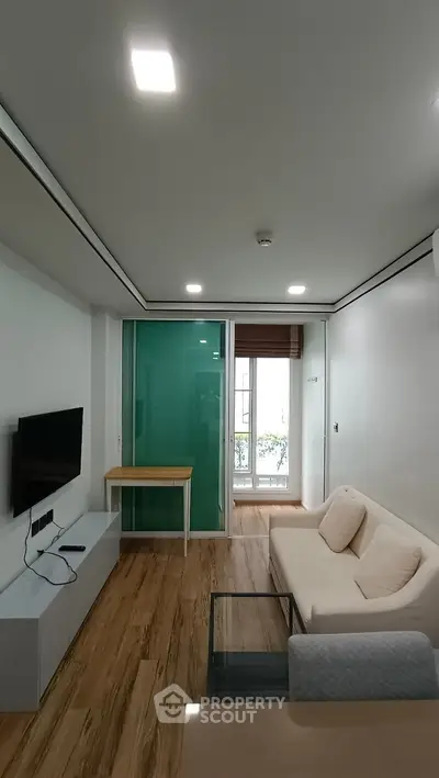 Modern living room with sleek design, featuring a wall-mounted TV, comfortable sofa, and stylish glass coffee table.