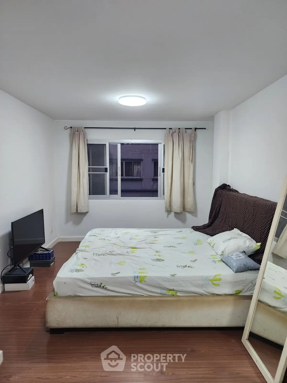 Cozy bedroom with modern decor and large window offering natural light.