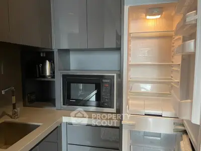 Modern kitchen with sleek cabinetry, built-in microwave, and open fridge showcasing ample storage space.