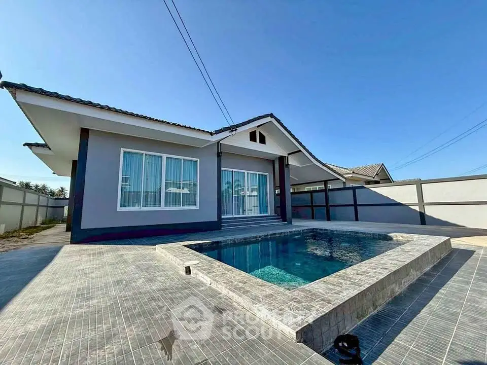 Modern single-story house with private pool and spacious patio under clear blue sky.