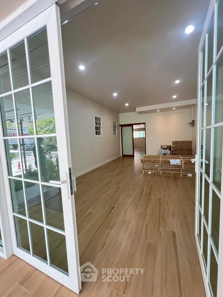 Spacious open-plan living area with wooden flooring and sliding glass doors, perfect for modern living.