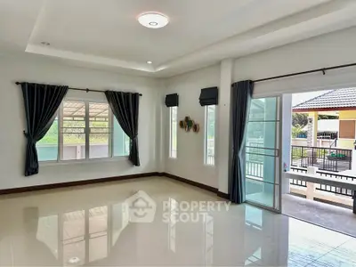 Spacious living room with large windows and sliding glass doors opening to a balcony.