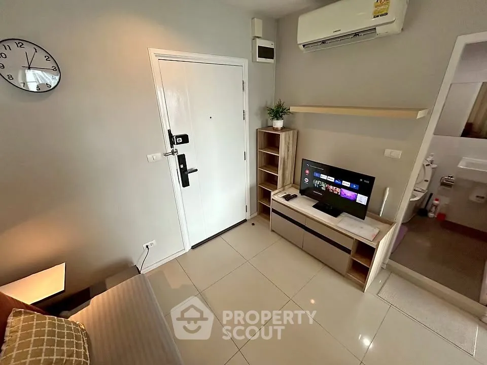 Modern living room with sleek furniture and wall-mounted TV, showcasing a compact yet stylish interior design.