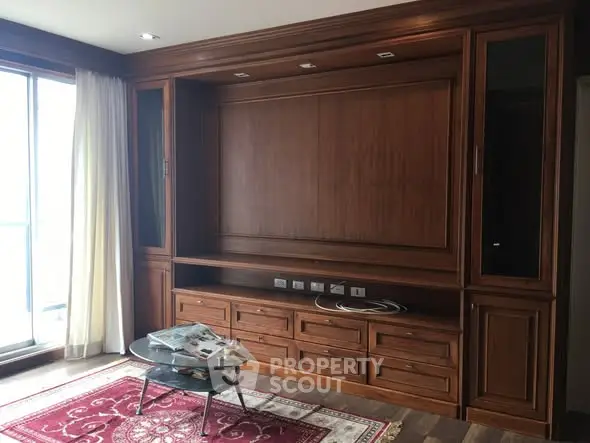 Elegant living room with wooden built-in entertainment center and glass coffee table.