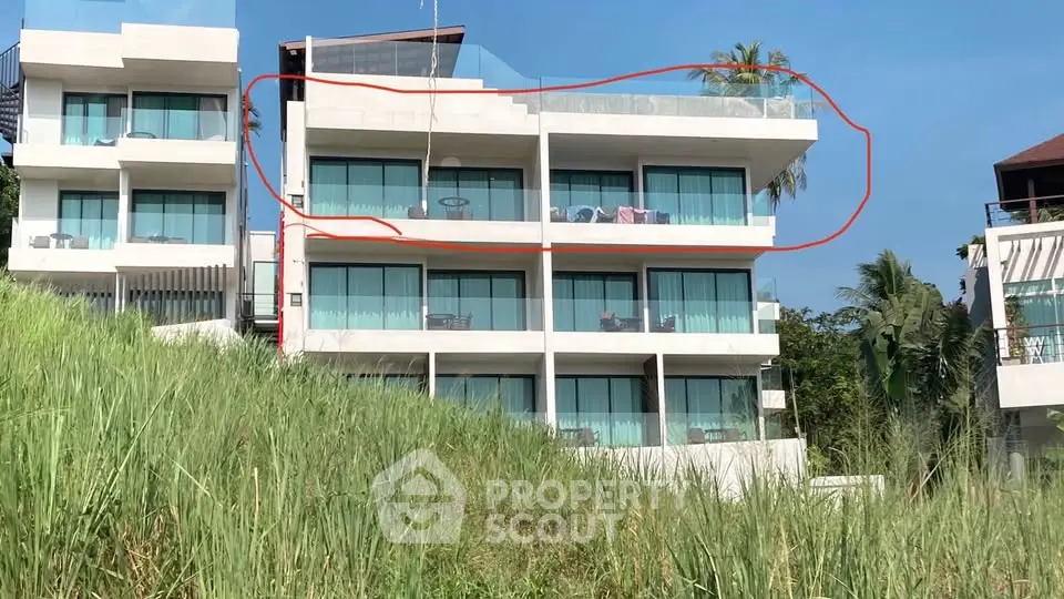 Modern multi-story building with glass balconies and lush greenery