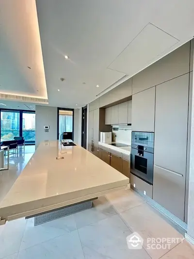 Luxurious modern kitchen with sleek cabinetry and spacious island in upscale apartment.