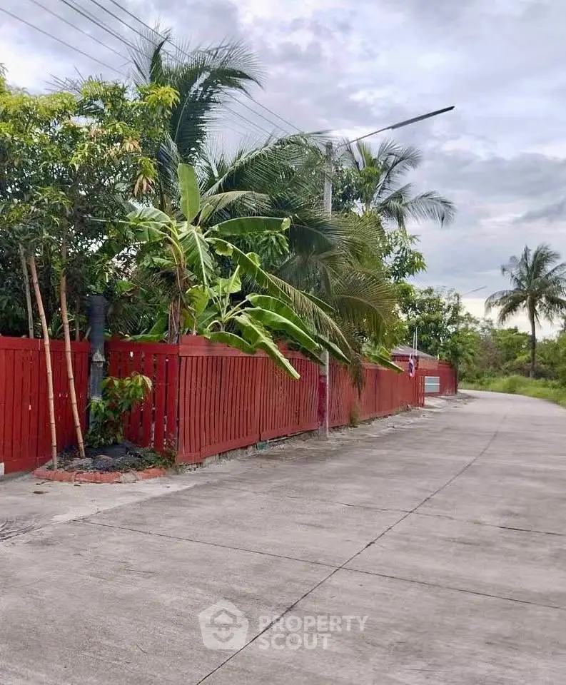 Charming tropical property with red fence and lush greenery