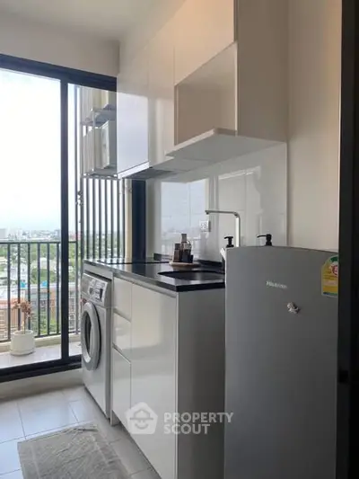Modern kitchen with washing machine and balcony view, compact and efficient design.