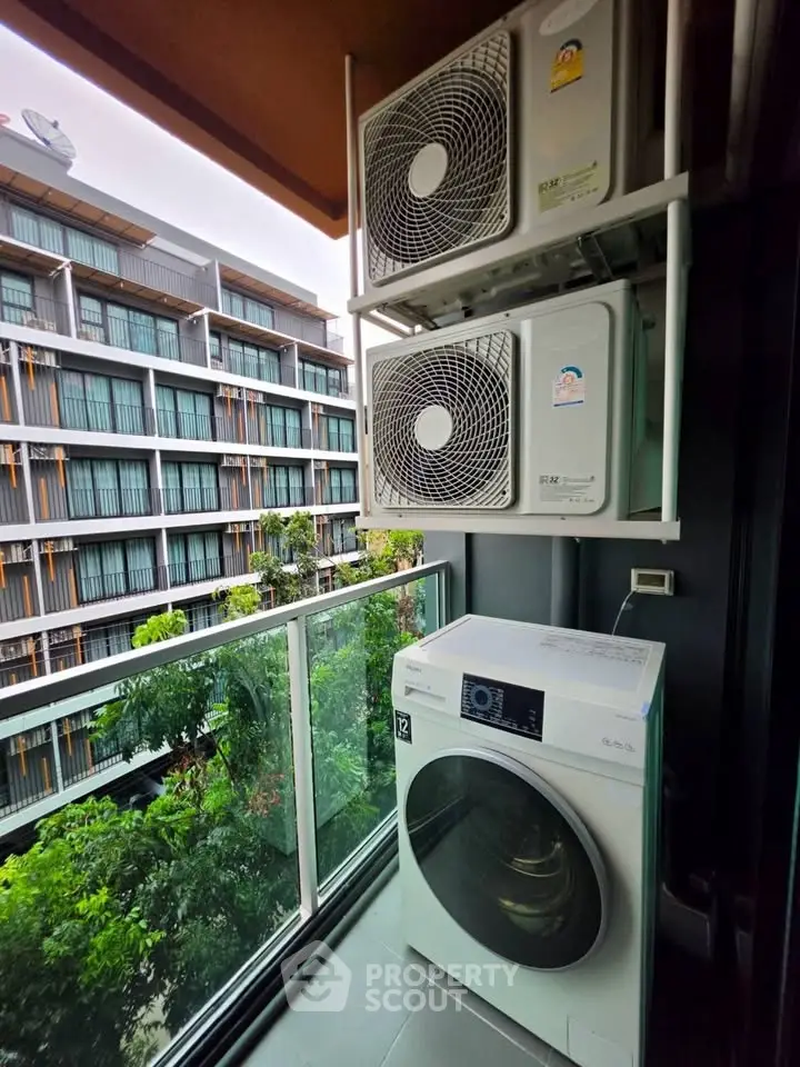 Modern balcony with washing machine and air conditioning units overlooking a contemporary building.