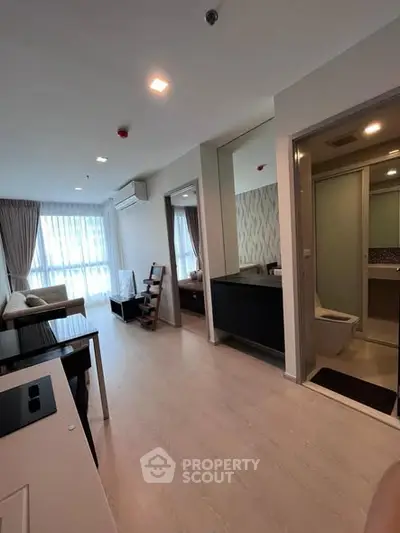 Modern apartment interior with open living area and bathroom, featuring sleek design and natural light.