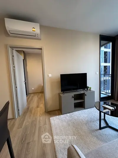 Modern living room with sleek TV stand, air conditioning, and balcony access in a stylish apartment.