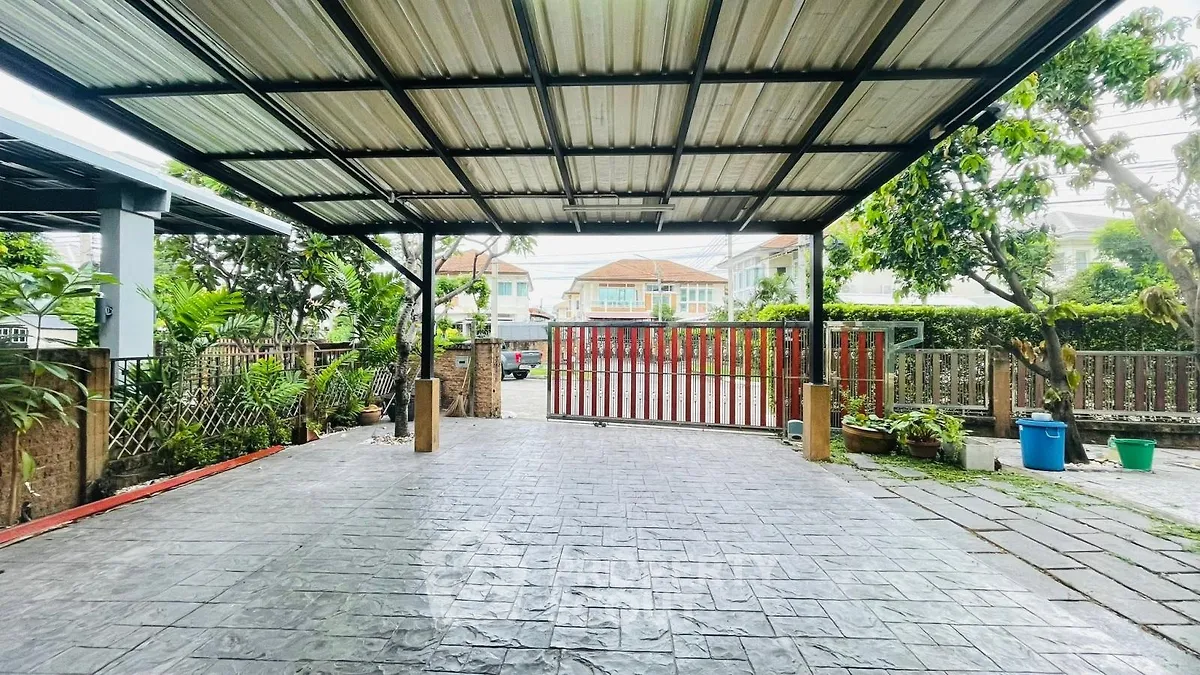 Spacious covered parking area with gated entrance and lush greenery