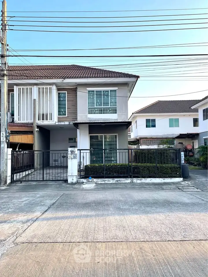 Charming two-story house with modern facade and gated driveway in a serene neighborhood.
