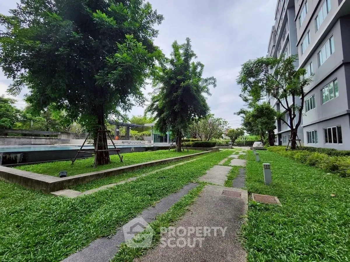 Lush green garden area beside modern apartment building with pathway