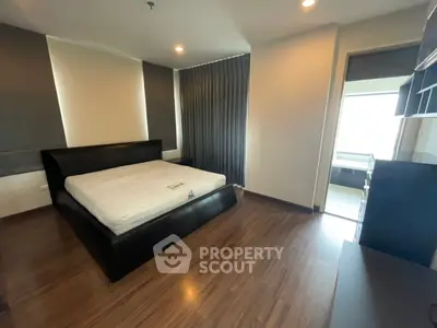 Spacious modern bedroom with sleek wooden flooring and large windows for natural light.