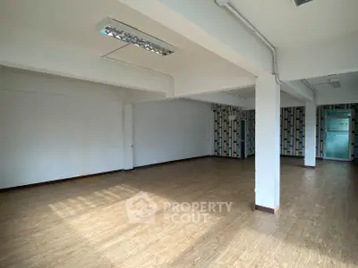 Spacious open-plan room with wooden flooring and modern lighting, ideal for versatile use.