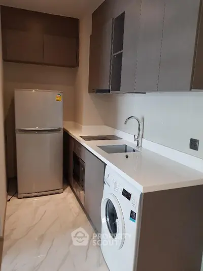 Modern kitchen with sleek cabinetry, washing machine, and fridge in compact layout.