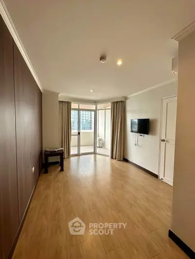 Spacious living room with wooden flooring and balcony view in modern apartment