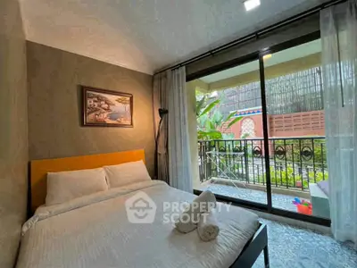 Cozy bedroom with garden view and balcony access, featuring elegant decor and natural light.