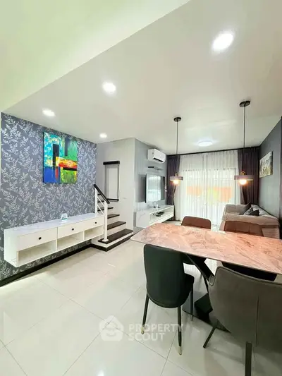 Modern open-plan living and dining area with stylish decor and elegant lighting.