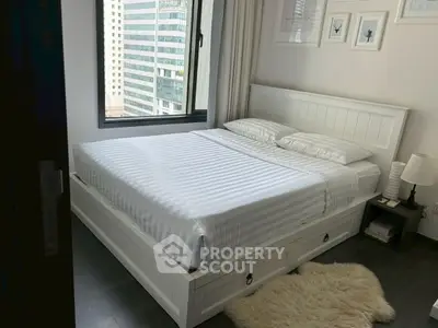 Modern bedroom with city view, featuring a sleek white bed and cozy decor.