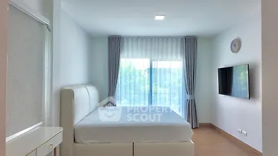 Modern minimalist bedroom with large window and wall-mounted TV, featuring sleek white furniture and soft natural light.