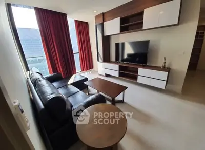 Modern living room with sleek furniture and large windows offering city views.