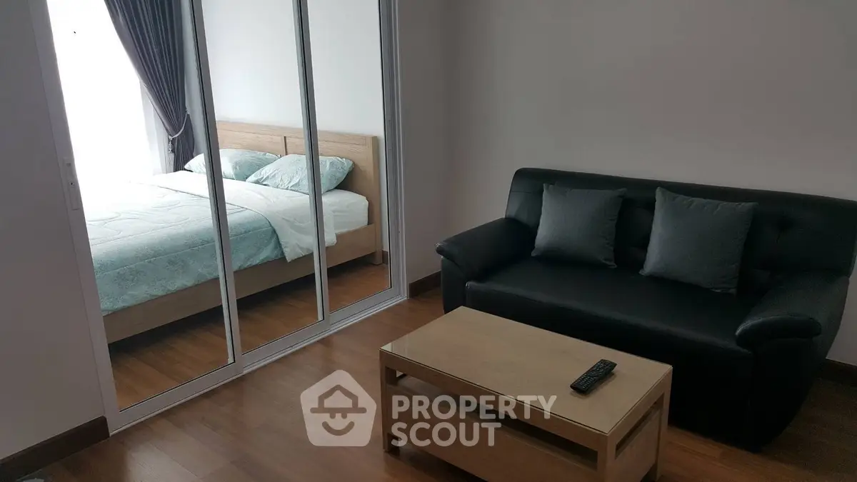 Modern apartment interior with cozy living room and stylish bedroom featuring mirrored closet doors.