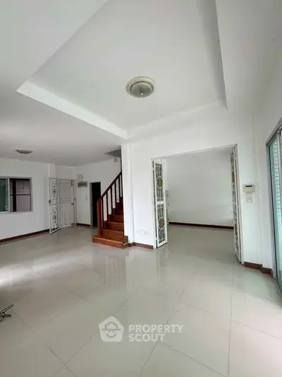 Spacious open-plan living area with elegant staircase and natural light