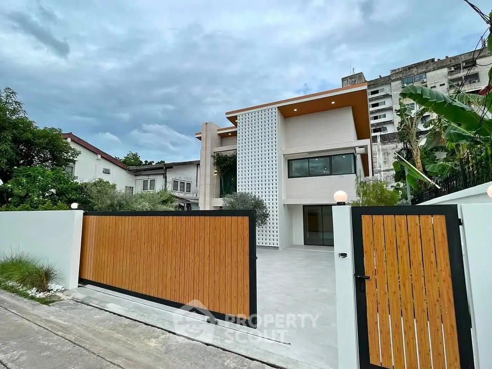 Modern two-story house with wooden gate and contemporary facade in urban setting.