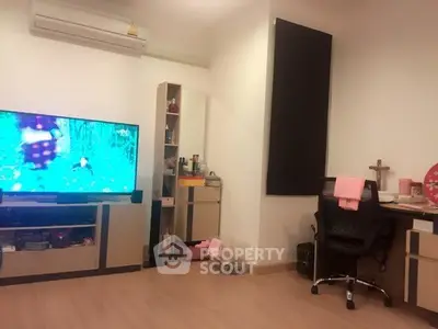Cozy living room with modern TV setup and home office corner, perfect for relaxation and productivity.