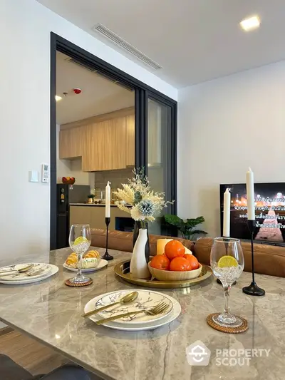 Elegant dining area with marble table and view into modern kitchen