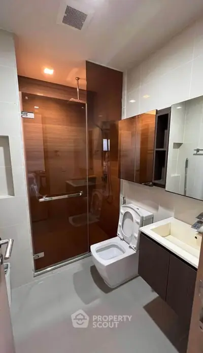 Modern bathroom with glass shower and sleek fixtures in contemporary apartment.