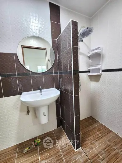 Modern bathroom with stylish tiles and round mirror, featuring a sleek sink and shower area.
