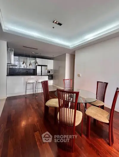 Modern open-layout kitchen and dining area with elegant wooden flooring and stylish furniture.