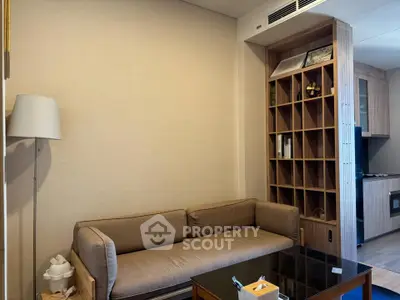 Modern living room with stylish sofa and built-in shelving, adjacent to a sleek kitchen area.