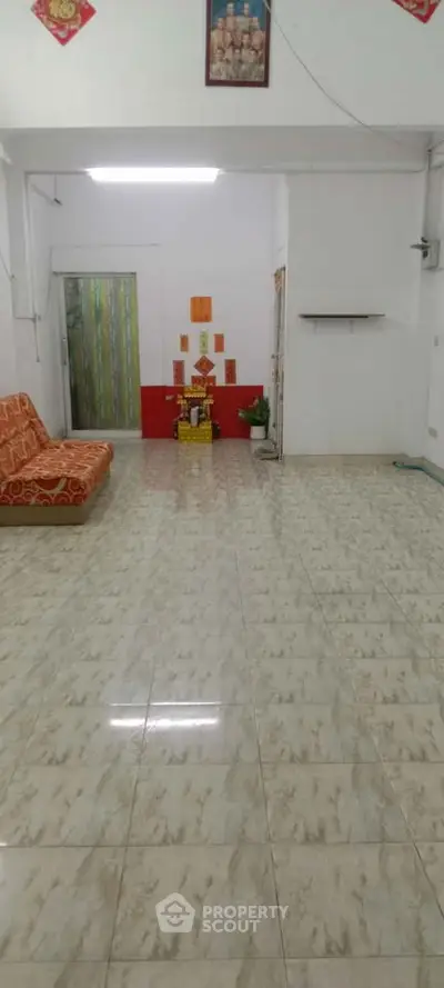 Spacious living room with tiled flooring and cozy sofa, ideal for family gatherings.