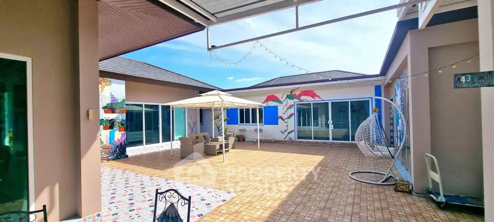 Spacious courtyard with modern patio furniture and artistic wall murals in a contemporary home.