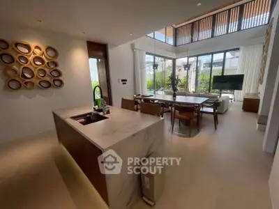 Luxurious open-plan living room with modern kitchen and elegant dining area, featuring large windows and stylish decor.