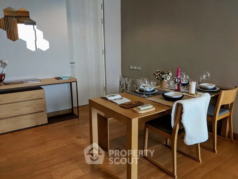 Modern dining area with wooden table and chairs, elegant table setting, and stylish decor.