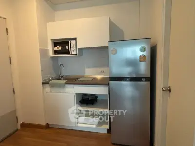 Compact modern kitchen with sleek appliances and wooden flooring, perfect for urban living.