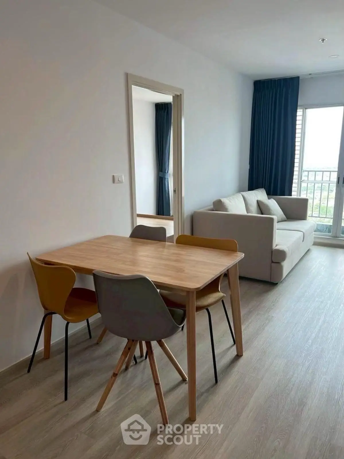Modern living room with stylish dining set and cozy sofa, featuring natural light and elegant decor.