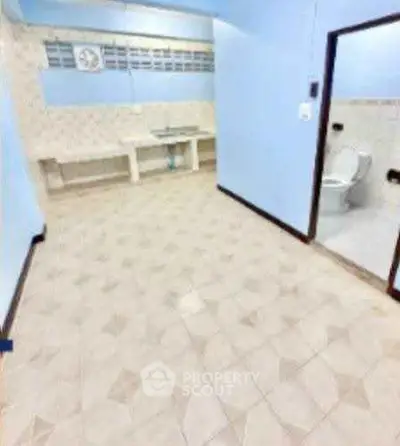 Spacious tiled room with attached bathroom, ideal for versatile use.