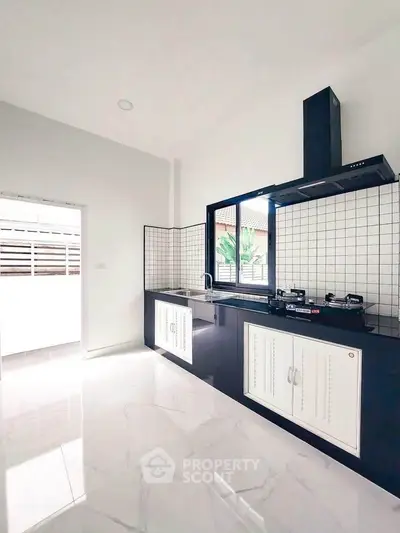 Modern kitchen with sleek black countertops and gas stove, featuring a bright and airy open layout.