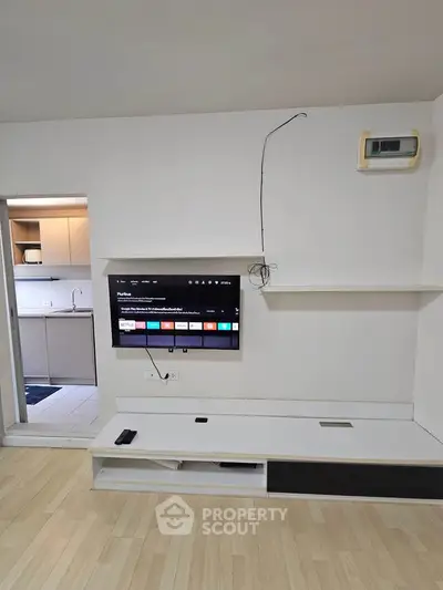 Modern living room with wall-mounted TV and sleek kitchen view