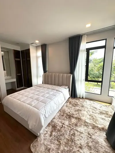 Spacious bedroom with large windows and plush carpet in modern apartment