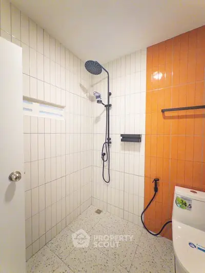 Modern bathroom with stylish shower and vibrant orange accent wall