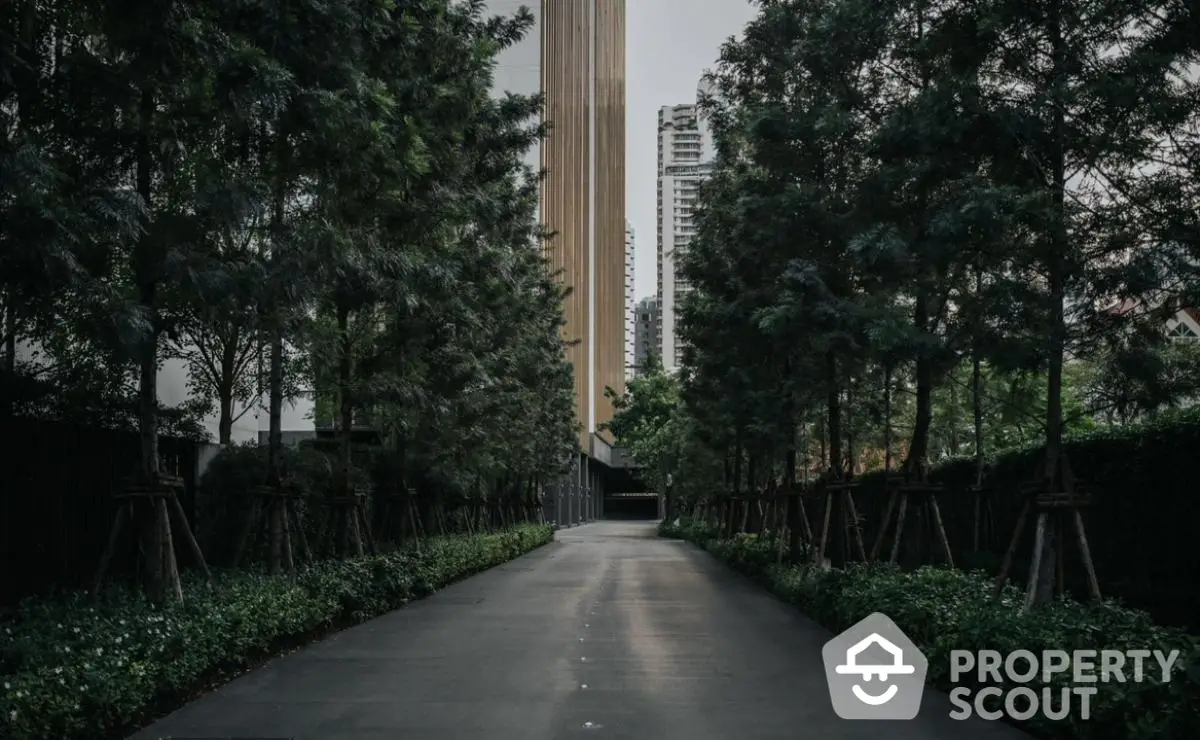 Elegant driveway leading to modern high-rise building surrounded by lush greenery