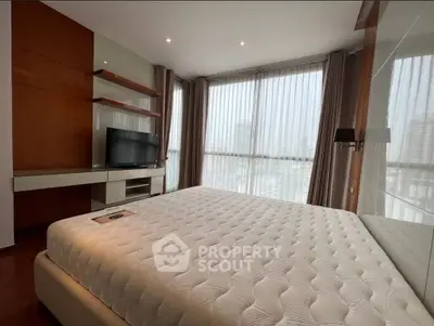 Modern bedroom with large windows and sleek furniture in a high-rise apartment.