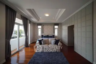 Spacious living room with elegant decor and large windows opening to a balcony.